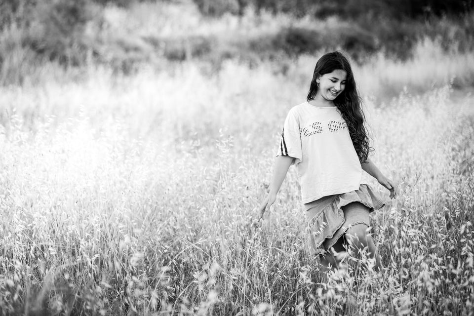 Jeune femme souriante qui marche dans les hautes herbes, en noir et blanc