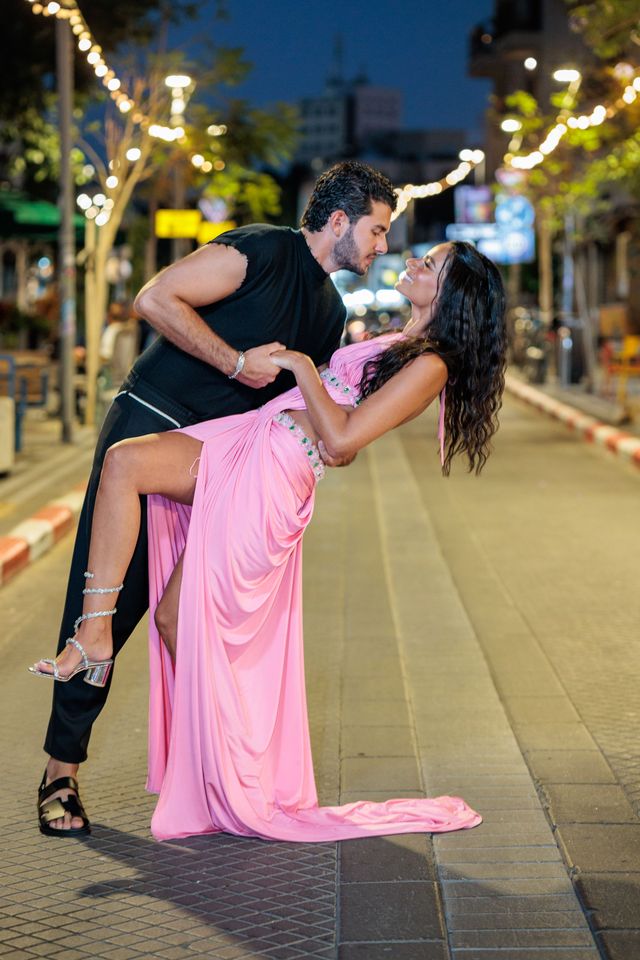 Couple qui danse dans une rue de Jaffa illuminée, la femme en robe rose renversée en arrière