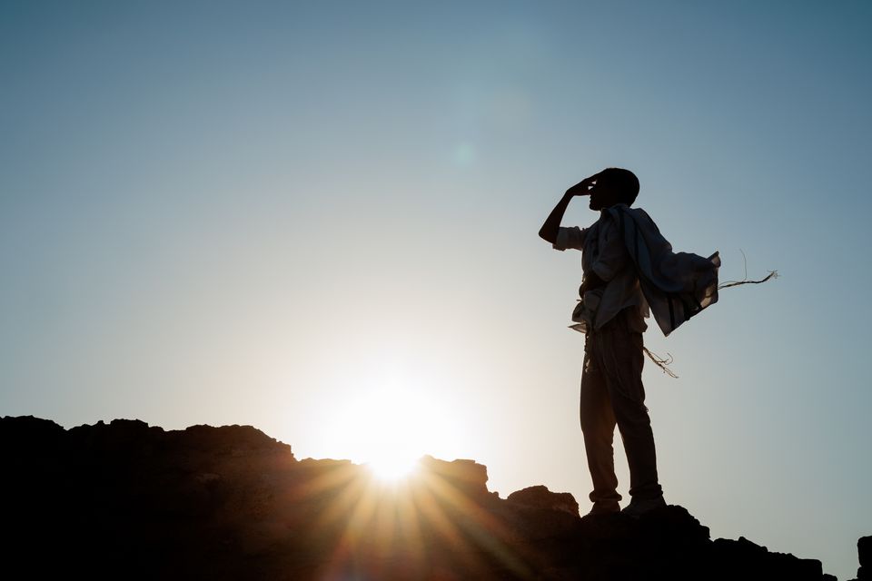 Silhouette sur les rochers face au soleil bas, le talit soulevé par le vent