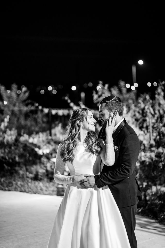 Le marié tient le visage de la mariée pendant leur danse, en noir et blanc