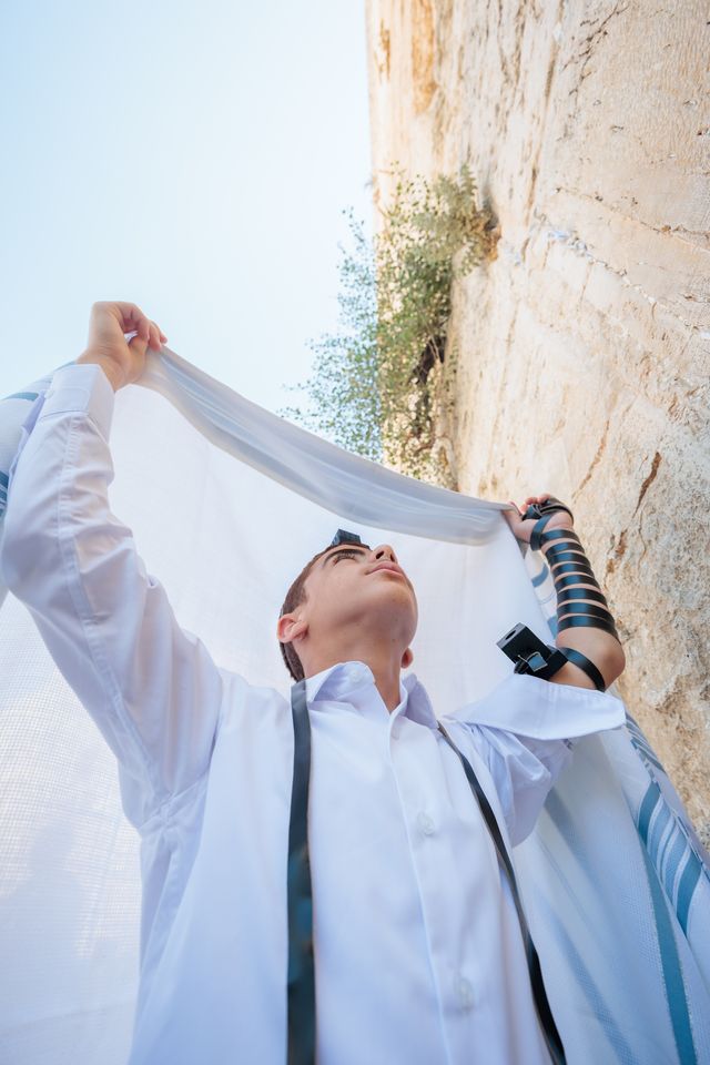 Garçon en tefilines qui lève son talith au-dessus de sa tête, au Kotel