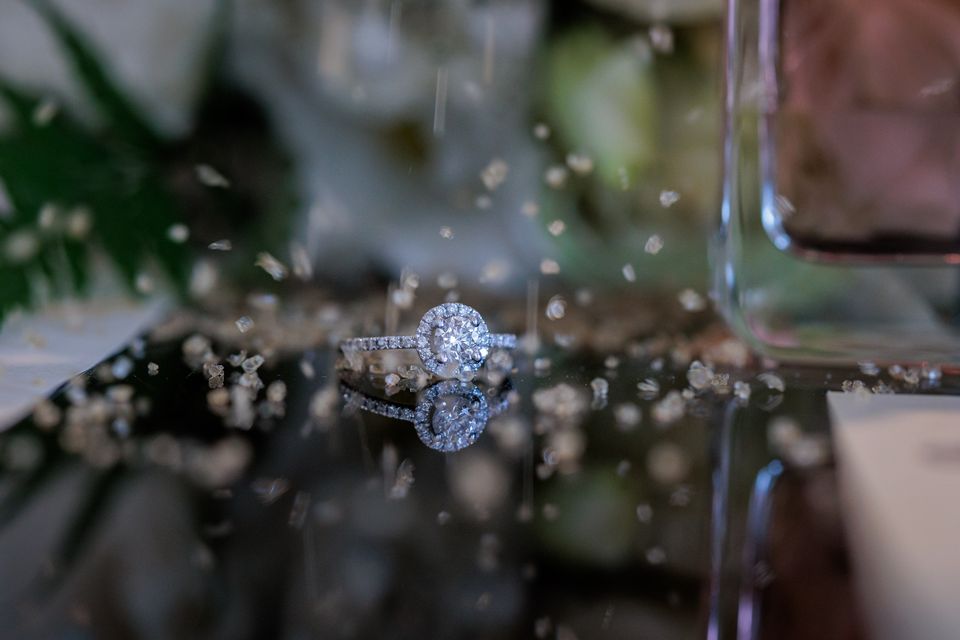 Bague de fiançailles posée sur une table miroir, entre des paillettes