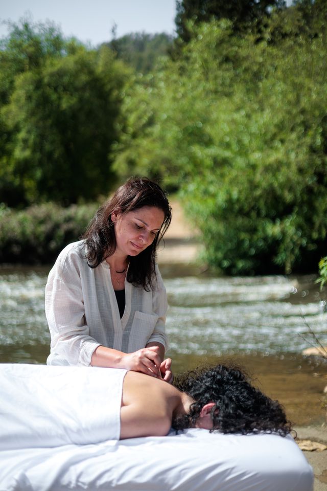Une masseuse soigne une cliente en plein air, au bord d'une rivière