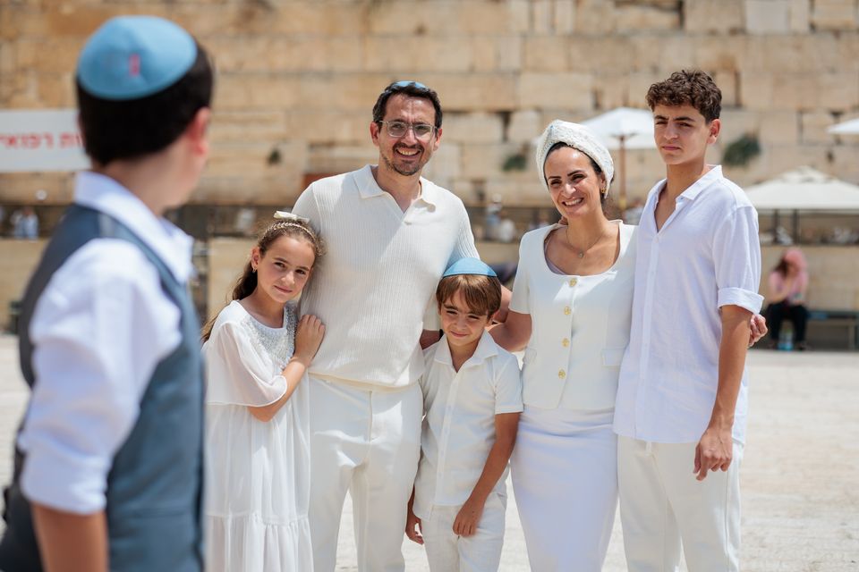 Famille habillée en blanc au Kotel, tournée vers le garçon de la bar mitsva